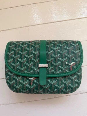 Grön axelväska  - Snygg grön axelväska  med klassiskt mönster i vitt och svart. Väskan har justerbar axelrem, silverfärgat spänne och är tillverkad i canvas med läderdetaljer. Perfekt för dig som gillar statement-accessoarer och exklusiv design. Bara att skriva vid några frågor. MVH Liam!! Pris kan diskuteras vid snabb affär. 