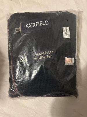 Fairfield svettäcke Champion marinblå - Svetttäcke Champion från Fairfield i marinblå färg med vit kant. Tillverkat i Waffle Tec-material som andas och transporterar bort fukt. Täcket har dubbla bröstspännen och broderad logga. Perfekt för häst efter träning. Aldrig använt. Storlek 145. 