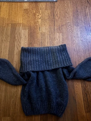 Grå stickad tröja från Gina Tricot - Mysig grå stickad tröja från Gina Tricot med bred polokrage och långa ärmar. Tröjan har ribbstickade detaljer vid krage, ärmslut och nederkant.