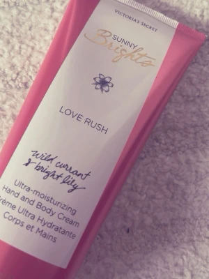 Victoria's Secret Love Rush - Ultra-moisturizing hand- och body cream från Victoria's Secret i doften Love Rush. Innehåller vildvinbär och lysande lilja, med en intensiv formula som återfuktar huden. Rosa tub med gulddetaljer, perfekt för att hålla huden mjuk och len. Ej använt helt ny bara öppnat och provat!