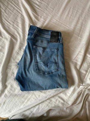 Blå jeans från replay  - Säljer ett par klassiska blå jeans från replay med snygga detaljer på bakfickorna. Jeansen har en mellanblå tvätt och är tillverkade i mjukt denimtyg. Perfekta för dig som gillar stilrena och tidlösa jeans. Säljer för att jag behöver pengar till sommaren. 👌🔛🔝💯