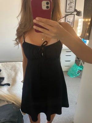 Svart kort klänning med knyt - Söt svart kortklänning med tunna axelband och knyt framtill. Klänningen har inga defekter och passar Xs-M, Perfekt för varma dagar eller när du vill känna dig extra fin 💕