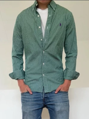 Olivgrön randig Ralph Lauren skjorta  - Olivgrön randig Ralph Lauren skjorta sitter i strl S. Mycket bra skick utan nåra defekter och hör gärna av er vid frågor elr funderingar!!