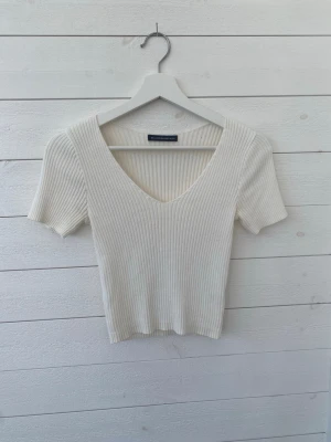 Brandy Melville top - Vit Brandy Melville top som är ribbad. Super fin och är använd fåtal gånger. Den har lite lätt gula fläckar i armhålorna, har tvättat den men går nog bort om man försöker lite mer. Står ingen storlek på den men skulle säga att den är xs/s