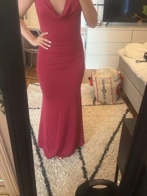 Röd långklänning med draperad urringning - Säljer en elegant röd långklänning med draperad v-ringad urringning och figurnära passform. Klänningen är ärmlös och har en mjuk, följsam känsla. Perfekt för dig som vill sticka ut på nästa fest eller bal. Kan bäras på flera sätt!!strlk s men passar m också 