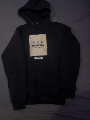 Svart hoodie från Burberry - Snygg svart hoodie från Burberry. Väldigt skönt material och bra luva på den. Har en väldigt bra passform. Finns kvitto men är försvunnen. Har bara testat den så den är helt ny! 
