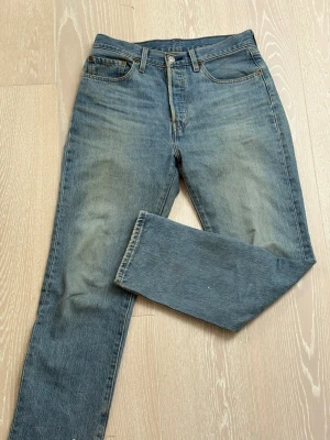 Levi's raka blå jeans - Klassiska blå Levi's jeans med rak passform och fem fickor. Jeansen har en vintage tvätt och är tillverkade i slitstarkt denim. De har knappgylf och bälteshällor, samt den ikoniska läderpatchen bak i midjan.