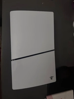 Vit PlayStation 5-konsol - Säljer en stilren vit PlayStation 5-konsol från Sony. Konsolen har en modern, kantig design med en matt finish och den klassiska PlayStation-loggan i hörnet. Perfekt för gaming och filmkvällar med vänner.