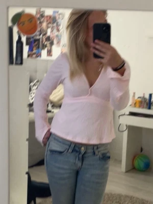 Ljusrosa omlottblus från Gina Tricot storlek Xs - Supersöt ljusrosa omlottblus från Gina Tricot med lång ärm och knytband i midjan. Blusen har en djup v-ringning och är gjord i ett lätt, krinklat tyg som ger en snygg struktur .
