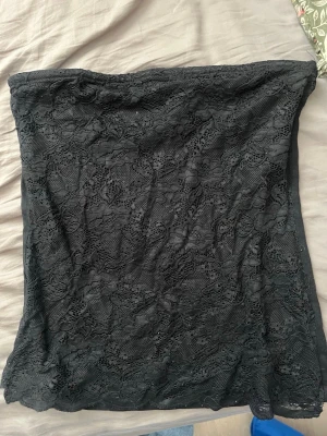 Svart spets tubtopp från H&M - Svart axelbandslös tubtopp från H&M med snygg spetsdetalj på framsidan av toppen. Storlek M 