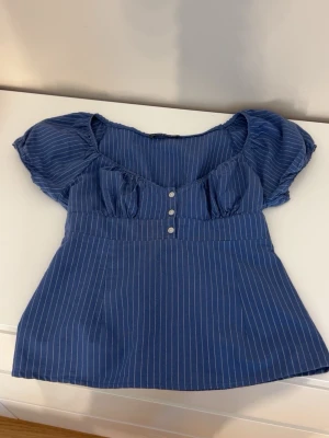 Blå randig topp från Brandy Melville - Supersöt blå topp från Brandy Melville med vita ränder och puffärmar. Aldrig använd!