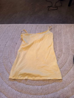 Gul linnetopp från Primark - Säljer en ljusgul linnetopp från Primark med tunna axelband och enkel, rak passform. Enkel att matcha med olika outfits. 