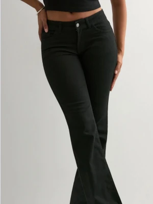 Svarta bootcut jeans med hög midja från Nelly.com - Snygga svarta bootcut jeans med hög midja och klassisk femficksdesign. Jeansen har utsvängda ben och stängs med knapp och dragkedja. Perfekta för en trendig och avslappnad look. Materialet ser ut att vara stretchigt denim för extra komfort.