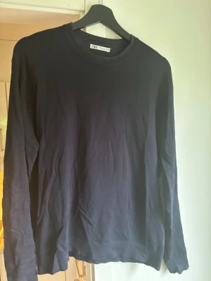Svart stickad tröja från Zara - En enkel och stilren svart stickad tröja från Zara med rund halsringning och långa ärmar. Perfekt basplagg till garderoben och lätt att matcha med olika outfits. Tröjan har ribbade muddar vid ärmslut och nederkant.