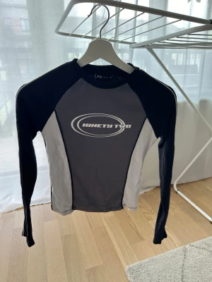 Svart och grå långärmad topp  - Sportig långärmad topp. Tight passform och rund halsringning. Perfekt för dig som gillar en sportig look.