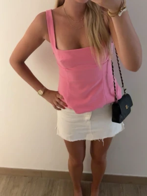 Trendig Zara topp - Trendig rosa linnetopp med breda axelband och fyrkantig urringning. Toppen har en croppad passform och är perfekt för varma dagar. Tillverkad i ett mjukt och lätt material som känns skönt mot huden. Enkel men snygg design som passar till mycket.