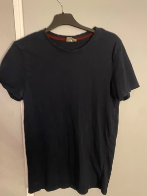 Mörkblå basic t-shirt - En enkel och stilren mörkblå t-shirt med rund hals och korta ärmar. Perfekt för dig som gillar minimalistisk stil och vill ha något som funkar till jeans eller shorts. Materialet ser ut att vara mjukt och bekvämt, troligen bomull.