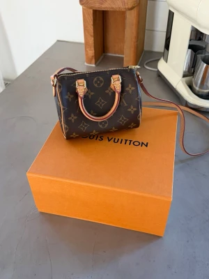Louis vuittom nano - Louis vuitton ”Nano speedy monogram canvas” 2020🌸 Mycket gott skick, bär inga spår av använding  Brun monongram canvas med detaljer i vachettaläder samt guldfärgad hardware. Etikettmärkt "LOUIS VUITTON PARIS made in france" samt med datecode (2020).  Originalkartong och dustbag medföljer. Rem ej avtagbar. 16 x 10 x 12 cm.
