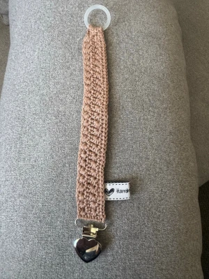 Virkad napphållare - Virkad, ljusbrun napphållare, virkad av mig i 100% bomullsgarn med metallclips och silikonring.  Mönsterskapare: animo.design