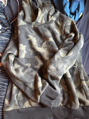 Säljer en grön kamouflerad hoodie - Hej! Säljer en grön kamouflerad hoodie med märket EP collection, jag tror att den är köpt från företaget Engelsons eftersom det står EP collection den är i Dam storlek 42/44 vilket är typ M/L, inga skador eller märken, kan skicka måtten vid intresse om man vill, nypris tror typ 200 eller nått men är inte säker. Inget fast pris