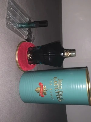 Jean Paul Gaultier Le Beau Parfum - Jean Paul Gaultier Le Beau Le Parfum är en elegant herrparfym i en mörkgrön, kroppformad flaska med gulddetaljer. Medföljer originalturkos plåtburk och en liten provflaska. Flaskan har en lyxig och unik design som sticker ut.