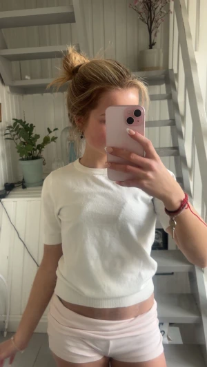 Vit croppad topp med kort ärm - En enkel och stilren vit croppad topp med korta ärmar och rund hals. Toppen har en ribbad kant nedtill och vid ärmsluten, vilket ger en snygg passform. Perfekt att matcha med både jeans och kjol för en clean look.