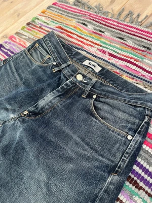 Mörkblå raka jeans från Acne - Säljer ett par mörkblå jeans från Acne med raka ben och klassisk femficksmodell. Jeansen har snygga slitningar och kontrastsömmar som ger en cool vintagekänsla. Perfekta för dig som gillar en avslappnad men stilren look. Skriv vid funderingar priset är inte fast!