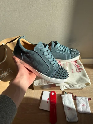 Christian Louboutin skor - Säljer dessa Christian Louboutin junior spike skorna. Skorna är helt nya, allt og ingår. 2st dustbags, extra nitar, extra skosnören och skohorn. Färgen heter hazel blue och är nästan lite turkosblå. Storlek 42,5. OBS, skolådan är en replacement box. Hör av er vid frågor!
