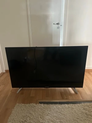 DigiHome svart platt-TV 55 tum - Säljer en stilren svart platt-TV från Digihome med metallfötter och tunn ram. Skärmen är cirka 55 tum och har en modern, minimalistisk design som passar perfekt i vardagsrummet eller sovrummet. Strömkabel medföljer.