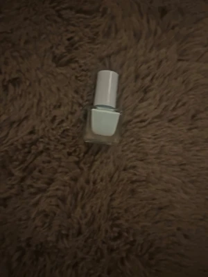 Ljusblått nagellack med vit kork - Snyggt ljusblått nagellack i en fyrkantig glasflaska med vit kork. Perfekt för dig som vill ha en fräsch och trendig look på naglarna. Lacket har en krämig finish och är lätt att applicera.