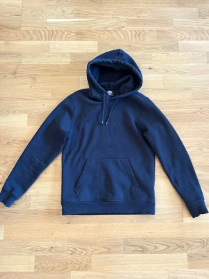 Svart hoodie med ficka - En stilren  hoodie från Dickies med klassisk känguruficka och justerbar dragsko i huvan. Perfekt för en avslappnad look och enkel att matcha med jeans.