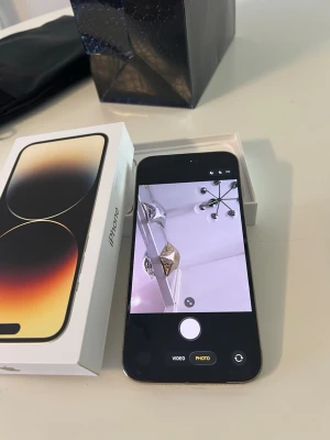 iPhone 14 Pro Max 128GB  - iPhone 14 Pro Max med 128GB lagring i svart. Snygg design med stor OLED-skärm och Dynamic Island. Glasbaksida och ram i rostfritt stål. Levereras med originalkartong. Perfekt för dig som vill ha en kraftfull och modern mobil.