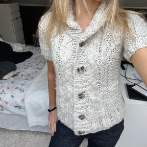 Stickad kortärmad kofta med knappar - Säljer denna söta stickade kofta i offwhite med knappar och bred krage. Koftan har korta ärmar och ett grovt stickat mönster som ger en mysig och trendig look. Storleken är M men skulle säga att den är mer som en S! 🩷
