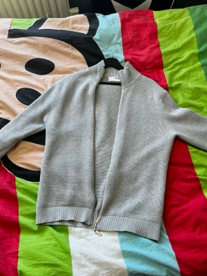 Ljusgrå  ziptröja - Snygg ljusgrå  ziptröja med hög krage och tvåvägsdragkedja.  Priset är ej hugget i sten, hör av vid minsta fundering.