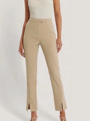 Beige kostymbyxa - Säljer beigea kostymbyxor från NA-KD med hög midja och raka ben. Byxorna har slits därfram samt fickor därbak. De har aldrig använts och är helt nya med prislapp på! 🥰