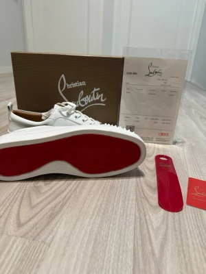 Christian Louboutin vita sneakers - Exklusiva vita sneakers från Christian Louboutin med ikonisk röd sula. Skorna är i läder och har klassisk snörning. Kommer med originalkartong, kvitto och skohorn. Perfekta för dig som vill sticka ut med stilrena detaljer och lyxig känsla. Kvitto och allt annat kommer med som förekommer på bilden.