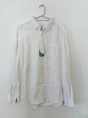 Vit klassisk skjorta från Glory day Helt ny och oanvänd med prislapp kvar. - Klassisk vit skjorta från Selected Homme med lång ärm, bröstficka och knappar framtill. Skjortan är tillverkad i mjuk bomull och har en tidlös, normal passform som funkar till många olika stilar.