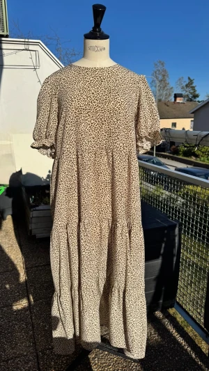 Leopardmönstrad maxiklänning 🐆 - Luftig och flowy långklänning i beige med leopardmönster. Perfekt för riktigt varma dagar. Korta puffärmar och rund halsringning. Avslappnad stil. Sätt på ett bälte så blir det oxå snyggt 👍🏻🤎👢