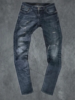 Nudie Jeans - Lean Dean - Säljer ett par marinblå skinny jeans från Nudie med slitningar och små hål. Strlk W29 L34. Hör av dig vid frågor!