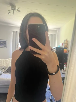 Svart ribbad ärmlös linnetopp - svart ribbad linnetopp med hög hals och ärmlös design. 