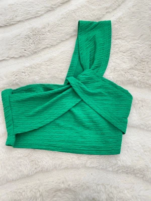 Grön oneshoulder croppad topp - Snygg grön croppad topp med oneshoulder-design och twistad detalj framtill, använd två gånger storlek s passar xs 