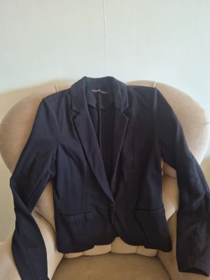 Svart figurnära bomull kavaj från Even&Odd stl M - Stilren svart kavaj från Even&Odd med klassisk krage och enkelknäppning. Kavajen har två fickor framtill och är gjord i ett mjukt tyg som ger en avslappnad men ändå dressad look. Perfekt att slänga över en t-shirt eller skjorta.