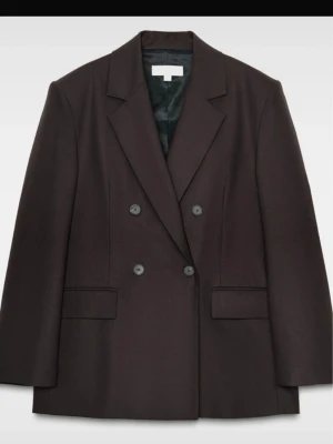 Mörkbrun dubbelknäppt kavaj - Stilren mörkbrun kavaj med dubbelknäppning och klassisk krage. Kavajen har två framfickor med lock och är helfodrad. Perfekt för en trendig och uppklädd look. Den är helt ny och oanvänd!