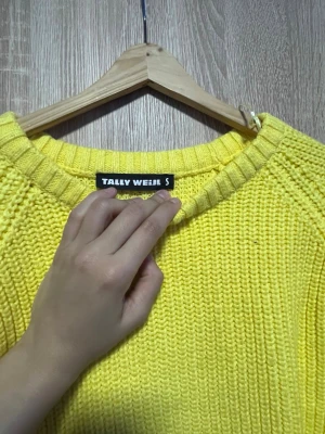 Gul stickad tröja från Tally Weijl - Säljer en solgul stickad tröja från Tally Weijl. Tröjan har en avslappnad passform, rund halsringning och breda ribbade muddar vid ärmsluten. Perfekt för att liva upp garderoben med en färgklick! Använt 2 gånger 