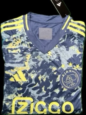 Ajax matchtröja blå/gul Adidas - Ajax matchtröja från Adidas i blått med gula detaljer och abstrakt mönster. Tröjan har V-ringning, klubbmärke och sponsorlogga framtill samt tre gula ränder på axlarna. Tillverkad i lätt och ventilerande funktionsmaterial.