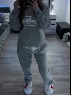 Grått corteiz set  - Mysigt grått loungewear-set med sweatshirt och matchande byxor. Båda delarna har ett vitt tryck framtill med motiv av ett tåg. Setet har avslappnad passform och är gjort i mjukt material, perfekt för hemmakvällar eller chill dagar.