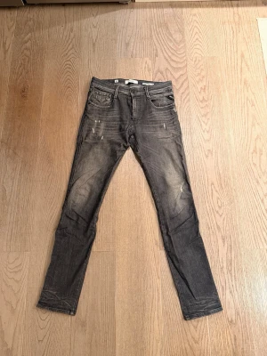 Replay anbas  - Säljer ett par svarta slim fit jeans med snygga slitningar och tvättade detaljer på framsidan. Modellen anbas storlek 32/34