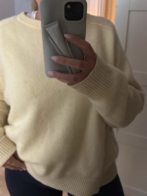 Ljusgul oversized stickad tröja från soft goat - Mysig ljusgul stickad tröja med avslappnad passform och breda ribbade muddar vid ärmslut och nederkant. Tröjan har rund halsringning och är perfekt för lager på lager. Materialet känns mjukt och behagligt mot huden. Storlek S