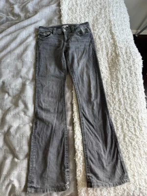 Grå bootcut jeans med låg midja - Säljer dessa jeans då de inte kommer till användning längre. De är från Gina Young i storlek 170. Knapparna på bakfickorna har ramlat av men de är inget man tänker så mycket på. De är i stretchigt material