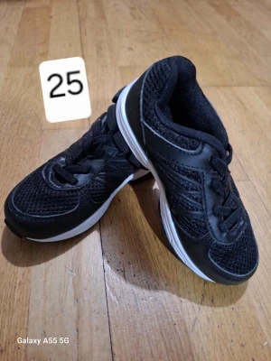 Svarta sneakers med vit sula - Snygga svarta sneakers med vit sula och svarta detaljer. Ovandelen är i mesh och syntetmaterial för bra andningsförmåga och komfort. Skorna har klassisk snörning och en sportig look som passar till det mesta.